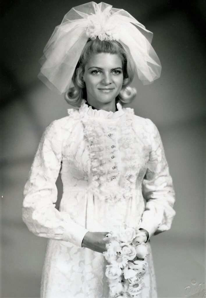 A woman in white dress with veil and hair bow.