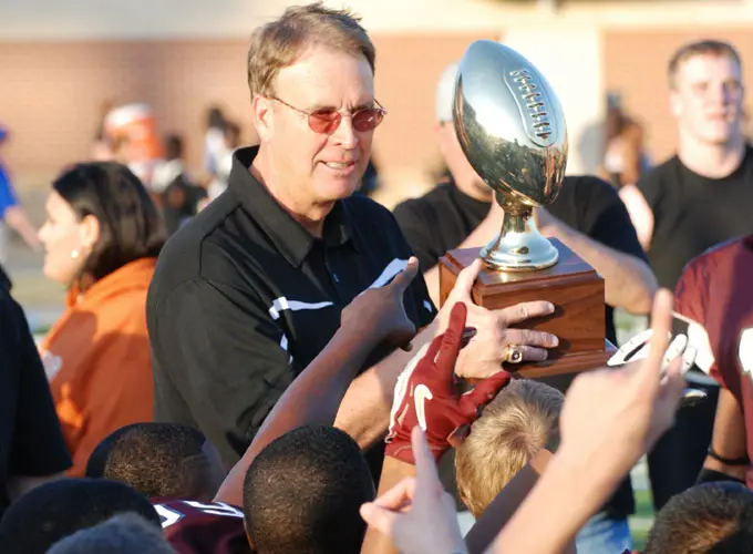 A man holding up a trophy while people watch.