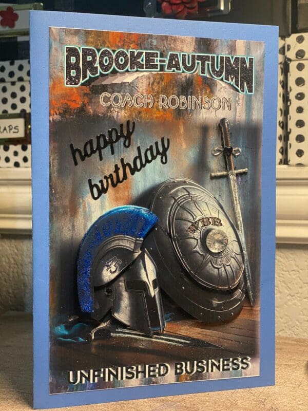 A birthday card with a helmet and sword.